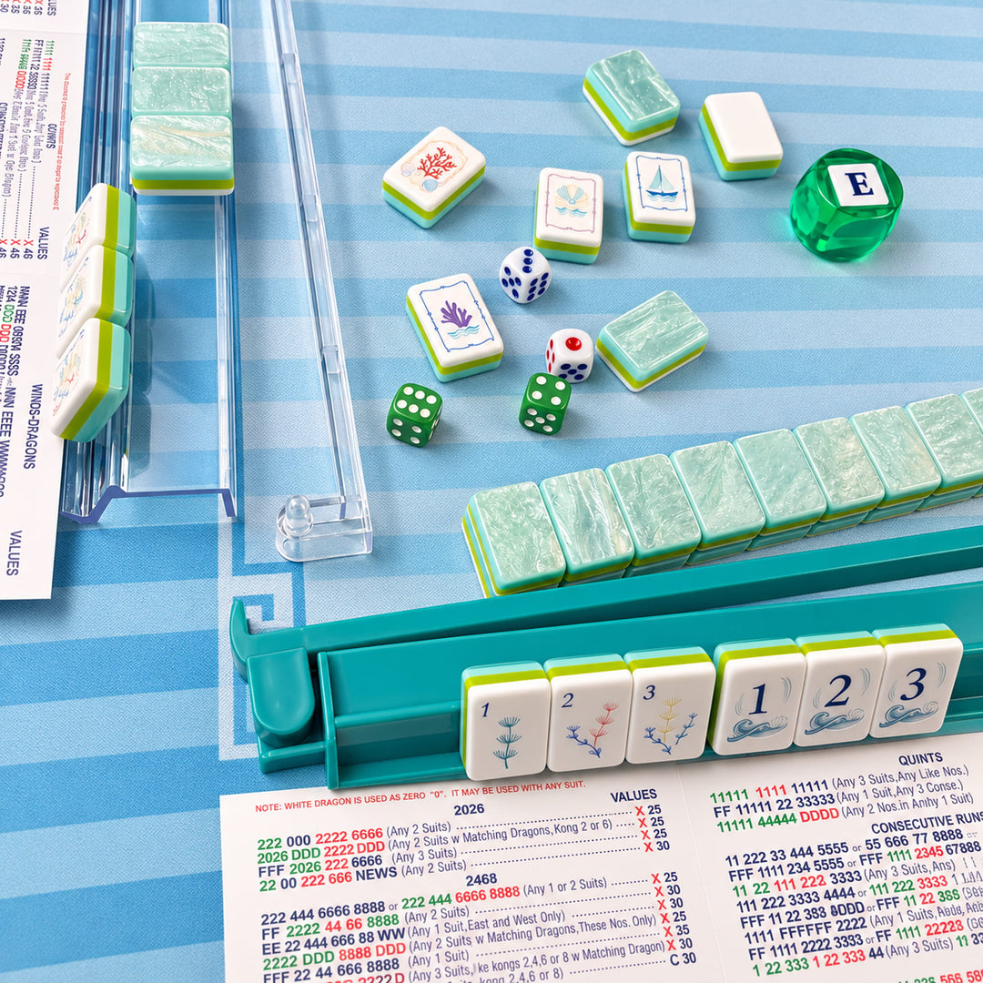 Coastal tabletop game night lifestyle setup for the large-size Ocean American Mahjong tile set from the Artistry Collection by The Mahjong Tile, featuring blue racks on a beachy mat.