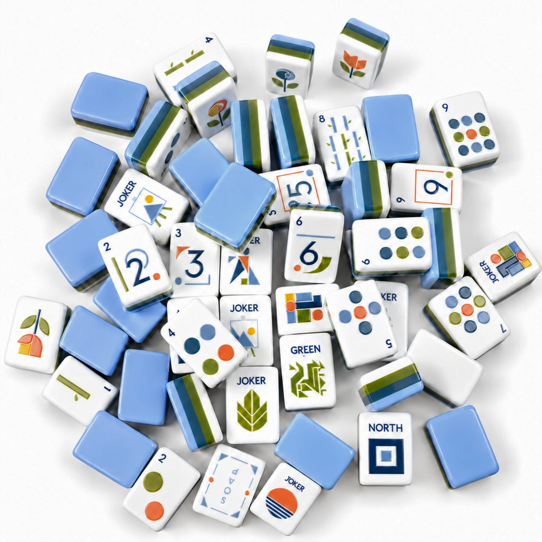 Scattered pile of Geometric American Mahjong tiles from the Artistry Collection by The Mahjong Tile, showing blue-green layered acrylic tile backs, sleek modern numerals, and minimalist geometric engravings.